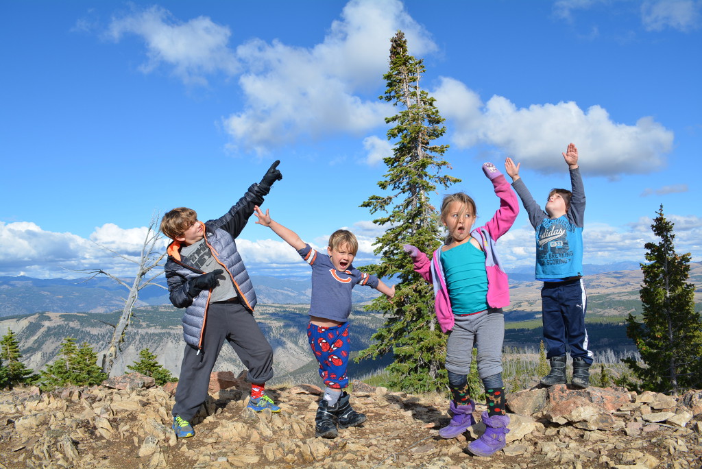 Four kids celebrating with mountains below and in the distance.