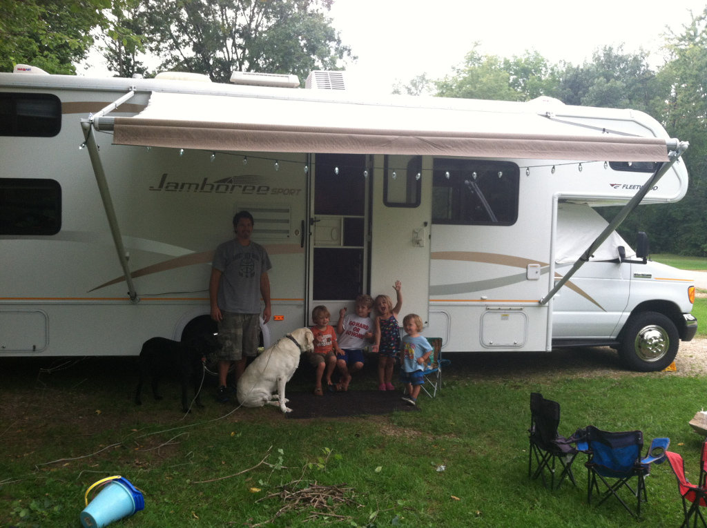 Man, 4 kids, and two dogs outside an RV.