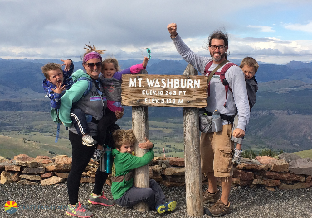 Family of 6 next to sign for Mt. Washburn with mountains in the distance.