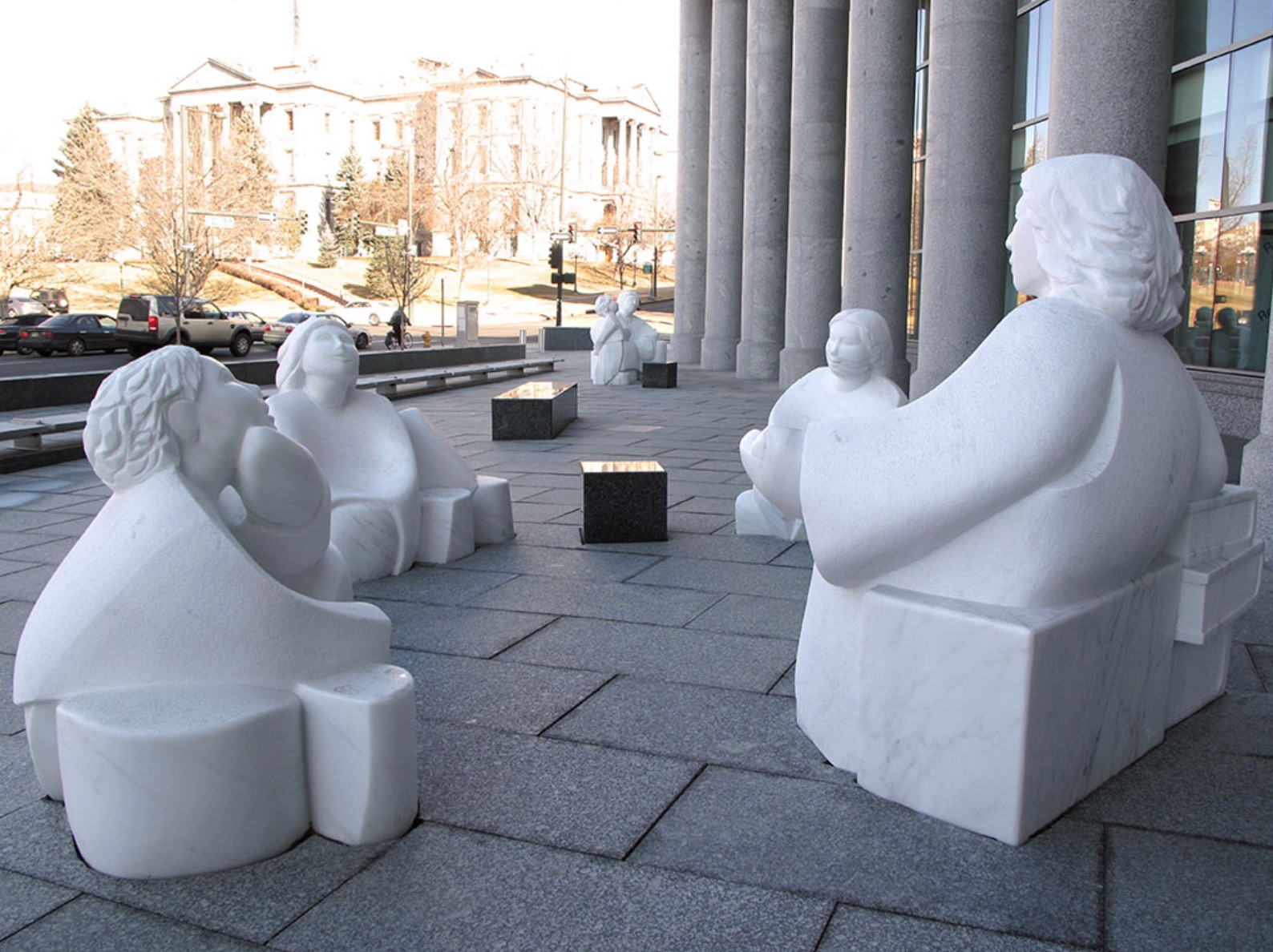 Sculptures resembling people outside a large building. 