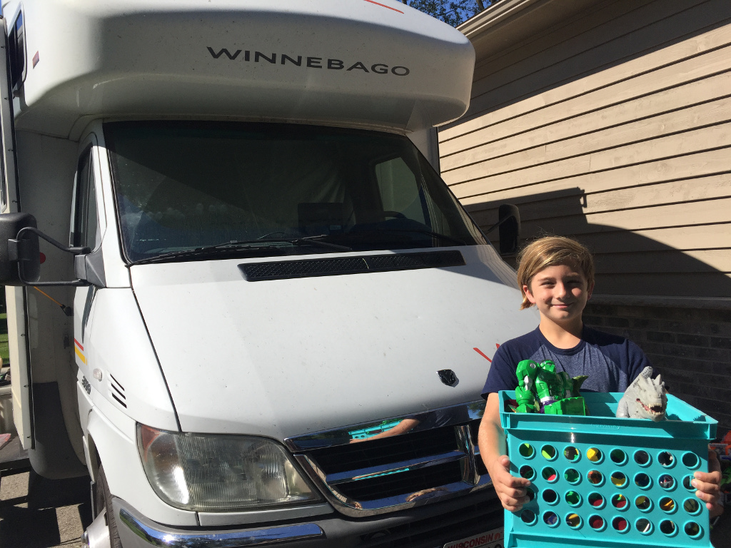 Carson standing in front of Winnebago View holding basket of toys