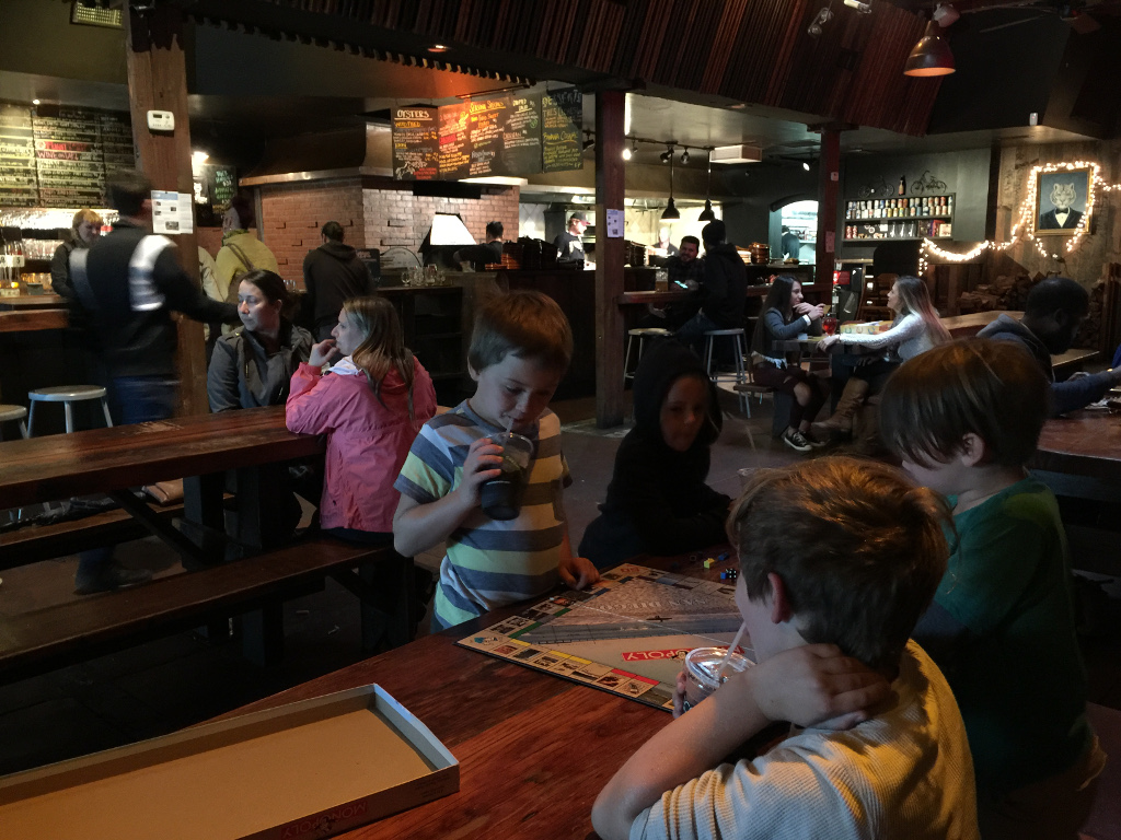 The kids at a table playing Monopoly at a brewery