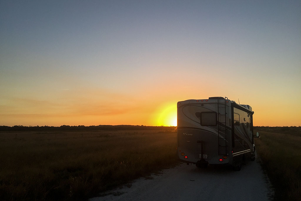Winnebago View parked on side of the road with sun setting on the horizon