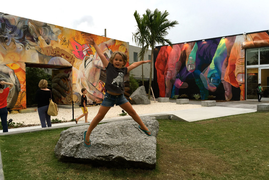 Child jumping off a rock with colorfully painted buildings behind