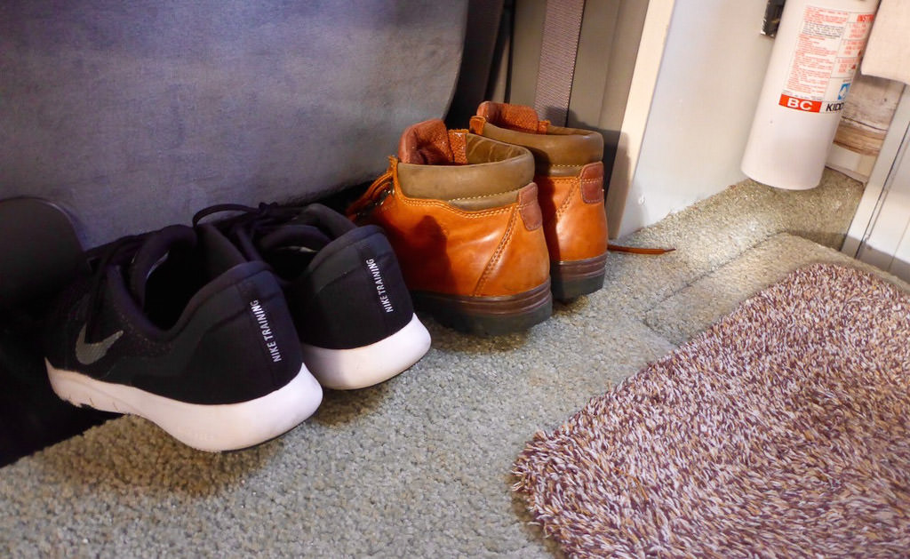 Two pairs of shoes tucked under passenger seat in RV