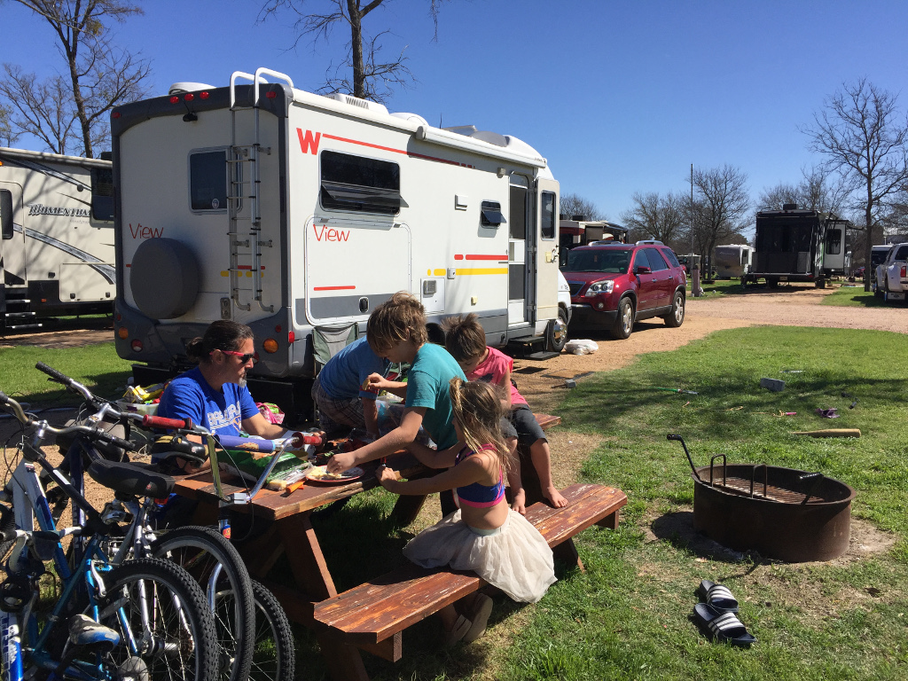 Family sitting at picnic table outside their Winnebago View
