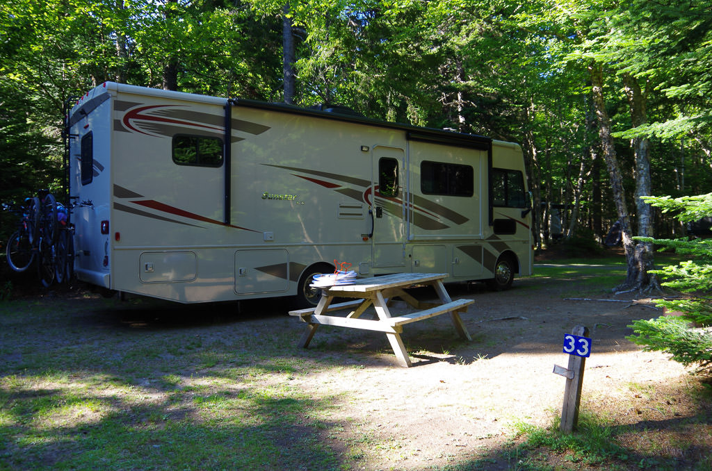 Winnebago Sunstar parked at campsite in campground with picnic bench out front
