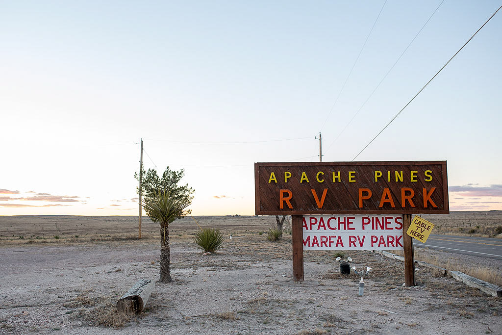 Sign for Apache Pines RV Park with desert in the background
